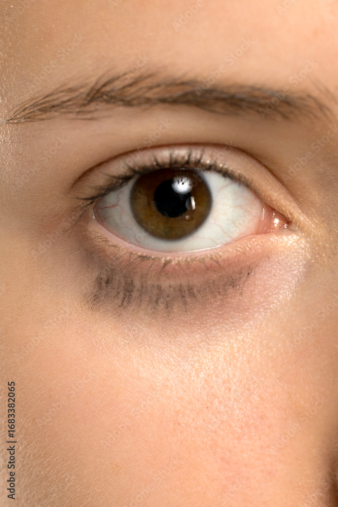 Obraz premium Studio shot closeup of young woman eye with mascara smudged under lower lashes on white background.