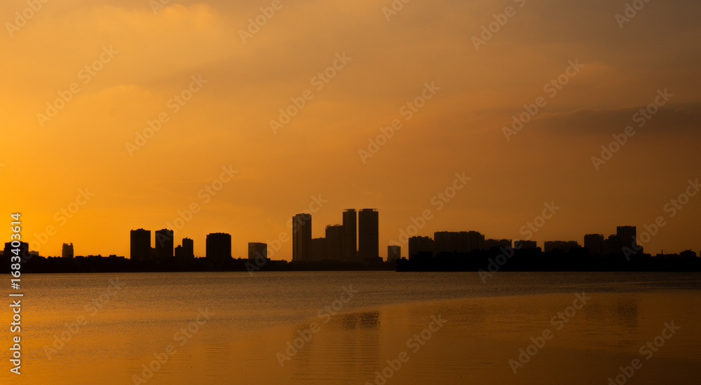 Fototapeta premium Golden sunset over the lake, silhouetted friends watching the glowing horizon in peaceful harmony.