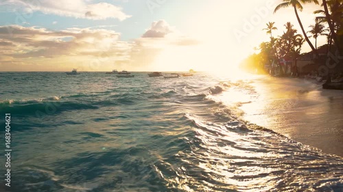 Riding low over turquoise waves in as they wash over a sandy beach in Punta Cana