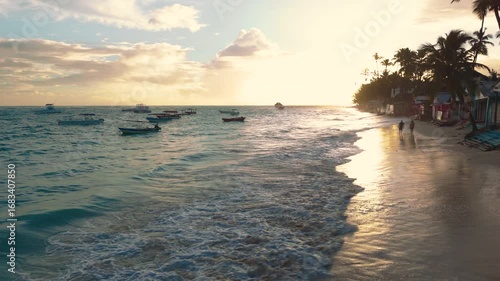 A couple in silhouette walk along a sandy Caribbean beach at sunrise