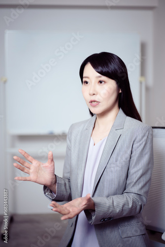 ホワイトボードの前でインタビューに応える女性2