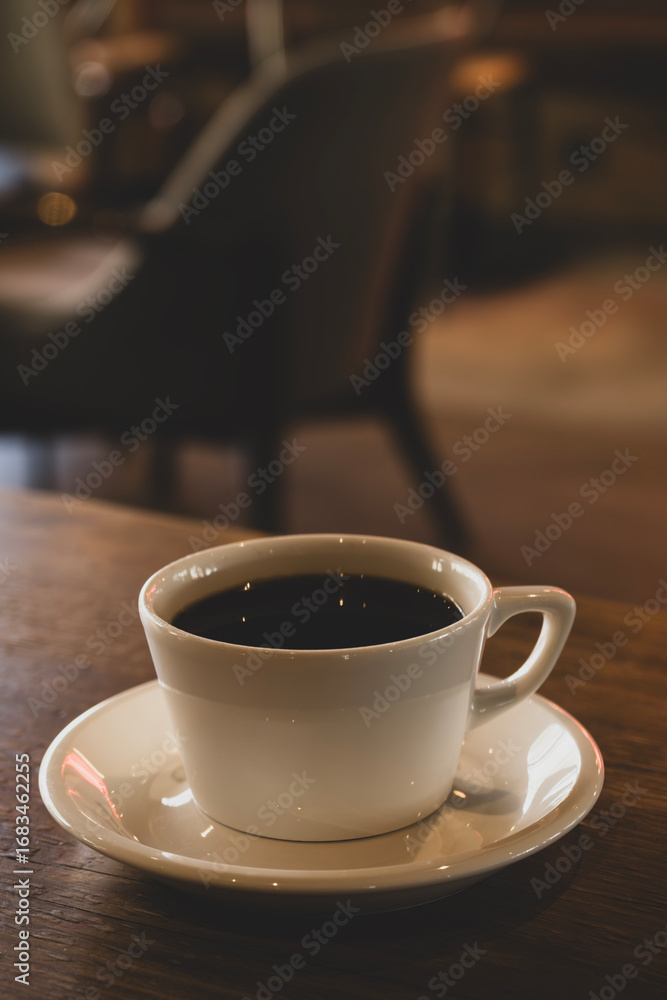 Obraz premium Hot coffee in white mug with dark backdrop. Freshly brewed coffee against black background. Cup of coffee on dark background.