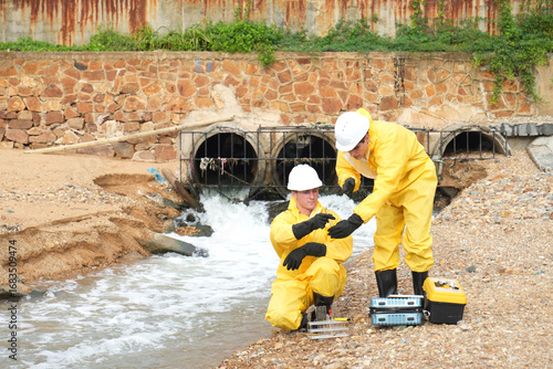 Environmental engineer or ecological scientist industrial worker in safety uniform working for inspect water quality at industry construction site near oil refinery plant by the sea.