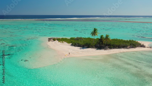 Aerial drone view of a young woman enjoying a sunny day on a remote tropical island with white sand and turquoise water