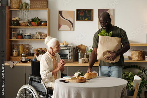 Fotografia Senior Caucasian woman with disability sitting in wheelchair at table smiling wh