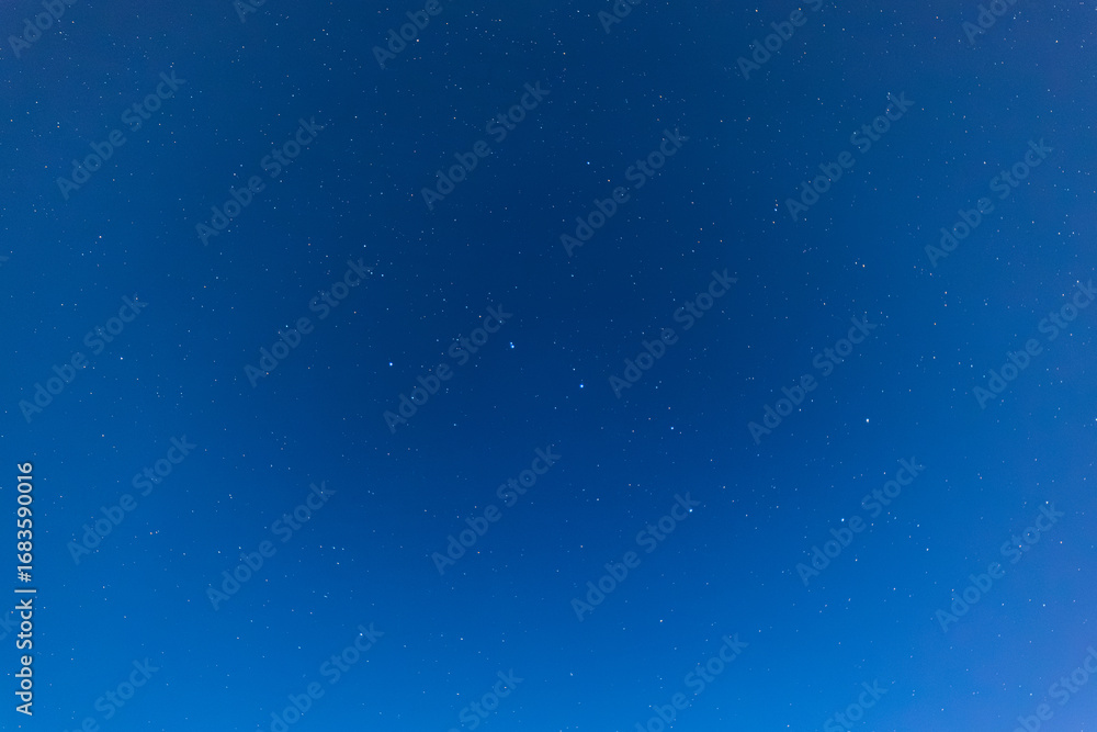 Fototapeta premium A serene night sky filled with countless twinkling stars scattered across deep blue darkness, capturing the quiet beauty of the cosmos.