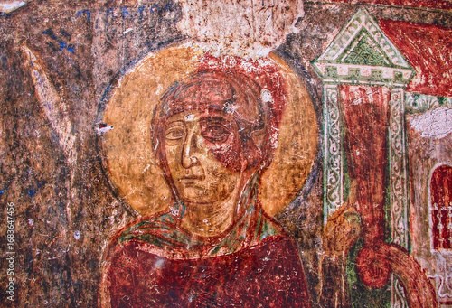 Ancient religious fresco depicting a saint inside a historic church from the medieval era