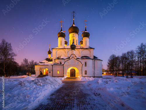 Beautiful ancient orthodox church illuminated at dusk with snowcovered ground and starry sky