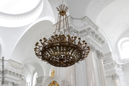 There is a beautiful huge chandelier hanging from the ceiling in the church.