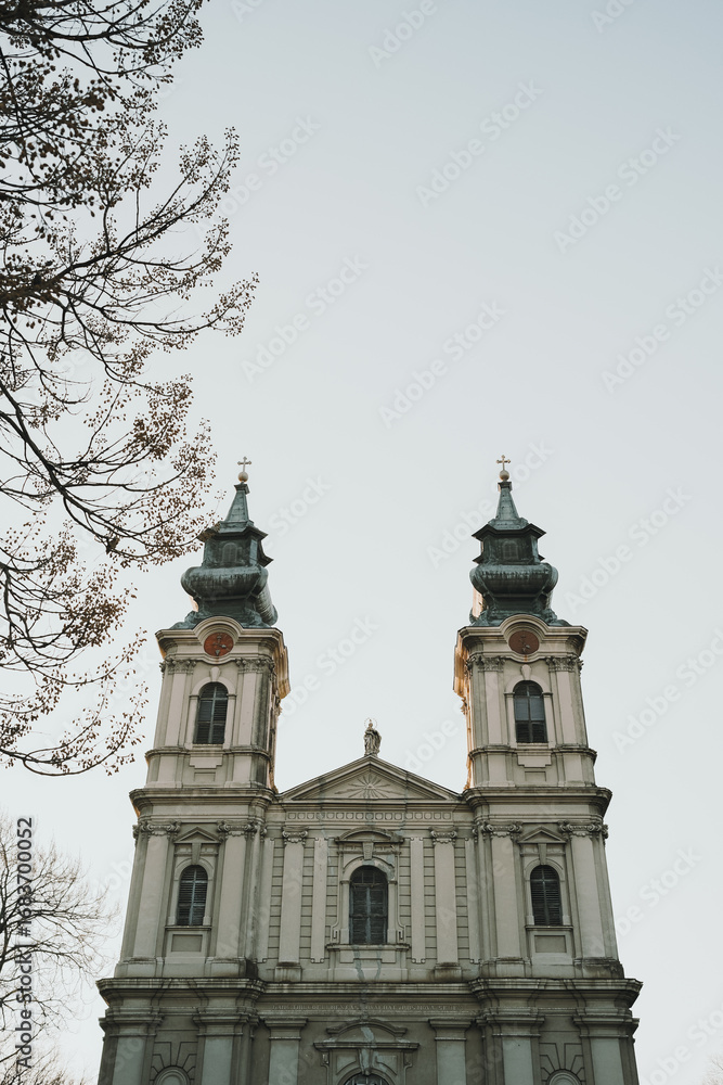 Obraz premium Baroque Catholic church facade in Subotica, Serbia, with twin towers and statues under a clear winter sky