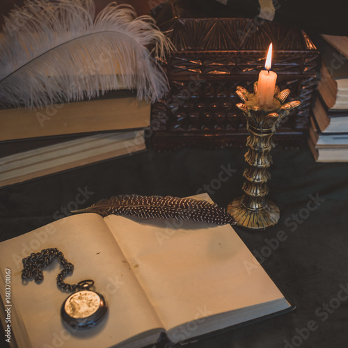 Book and candle on a vintage table, dark academia aesthetic. Evening time