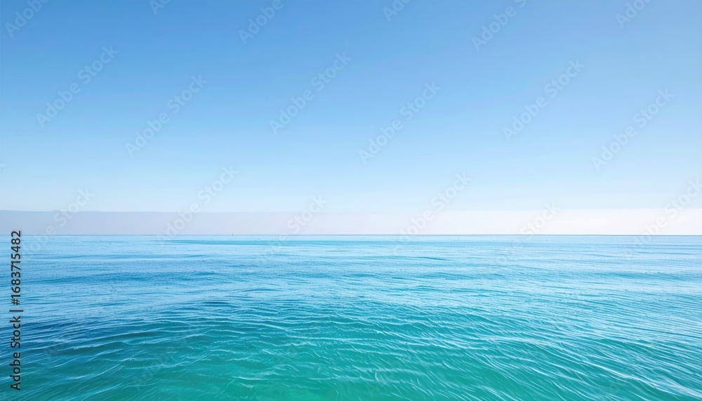 Obraz premium Wide shot of a tranquil ocean meeting a clear, bright sky