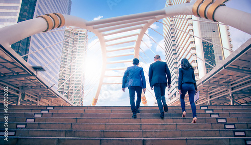 Rear view of business team climbing stairs go to a city at daytime. Business concept