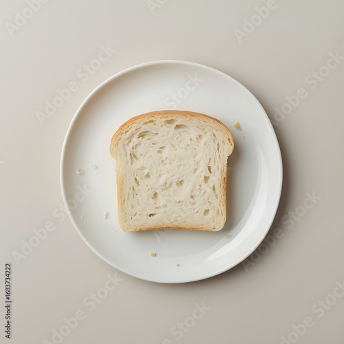 A single slice of white bread rests on a simple white plate presented from a top down perspective