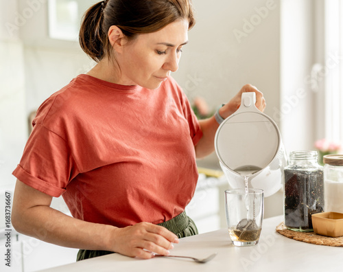 Canvas Print Woman Making Tea At Home In The Kitchen