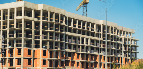Construction site showcasing progress on a multi-story building under a clear blue sky