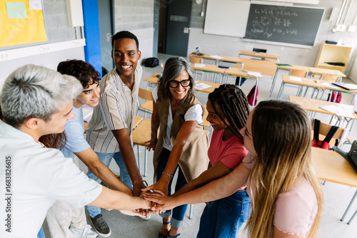 Wallpaper Mural Diverse group of young high school students stacking hands with middle age female teacher in classroom showing unity, motivation, support and cooperation. Education concept Torontodigital.ca
