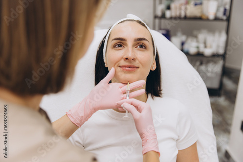 Fotografia Beautician injecting hyaluronic acid into woman's chin for lip augmentation