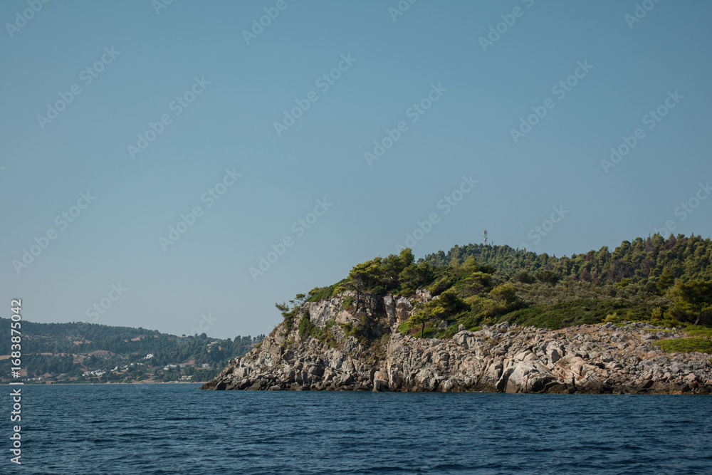 Naklejka premium Eine Insel im Meer. Felsen und Wälder. Blauer Himmel. Küste in Griechenland