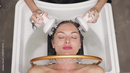 Woman receiving hydromassage head treatment in Japanese spa, relaxing in water with massager, surrounded by soothing ambiance and natural materials, promoting wellness and tranquility