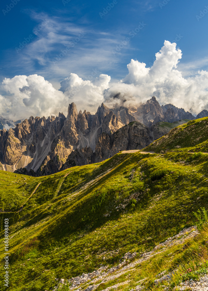 Fototapeta premium Alpine hiking trails cutting through rocky peaks of Dolomites with serene sky above. Captures spirit of outdoor adventure and pristine nature.