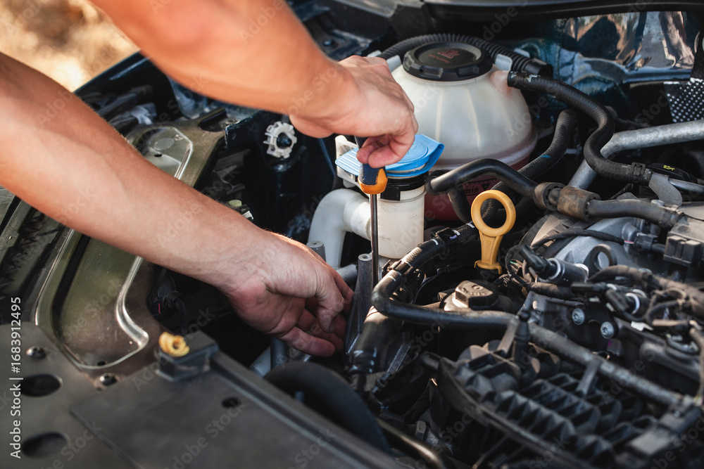 Obraz premium Engine maintenance being performed with a tool over a vehicle in a sunny outdoor location