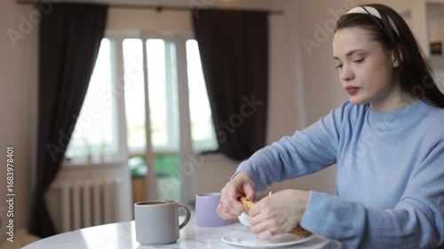 a young woman having breakfast at home at the table