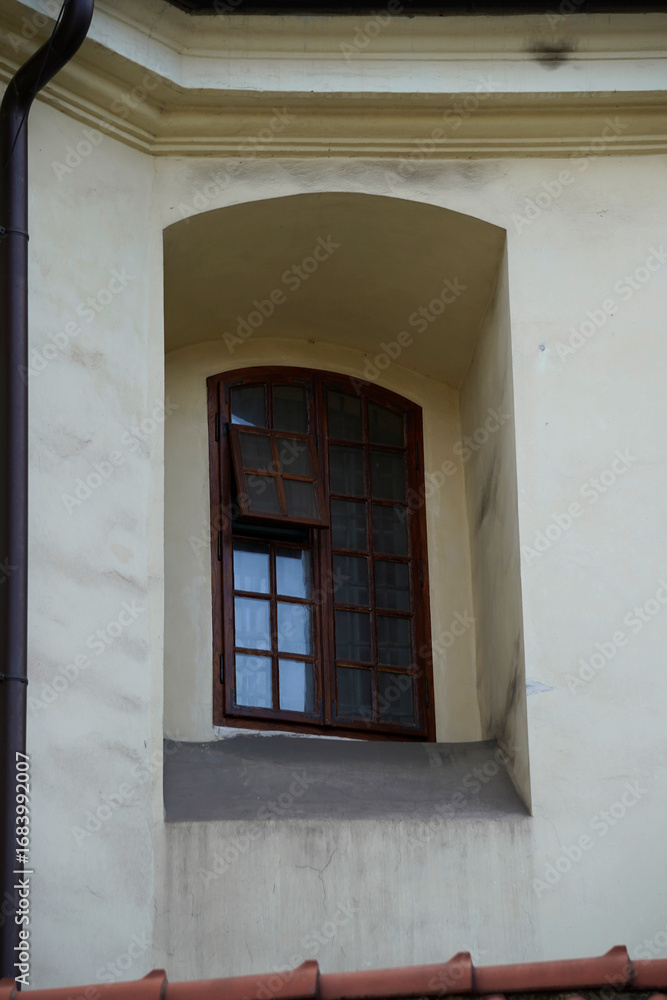 Obraz premium Arched window with wooden frames set in light facade, combining historic architectural charm with classical design elements