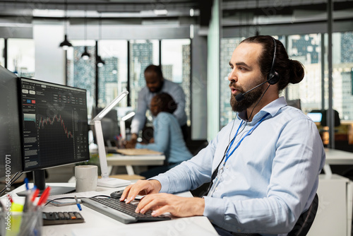 Fotografija Trader working for brokerage company talking with clients, explaining stock market trends through headset mic