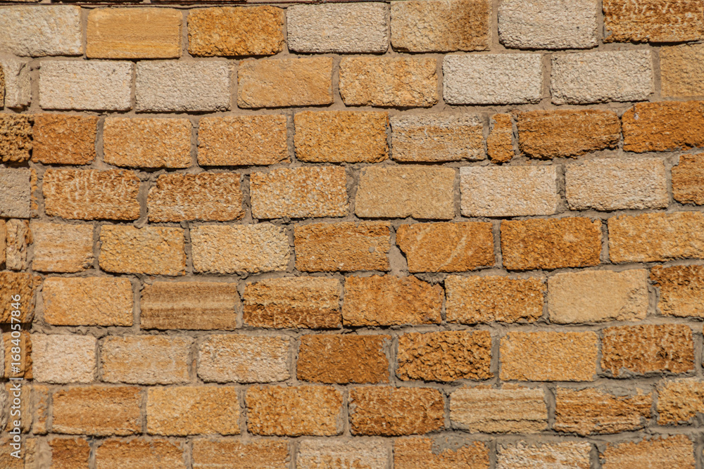 Obraz premium Close-up of weathered light brown bricks in an ancient Central European village, naturally lit with a warm glow The brickwork is laid evenly without mortar lines