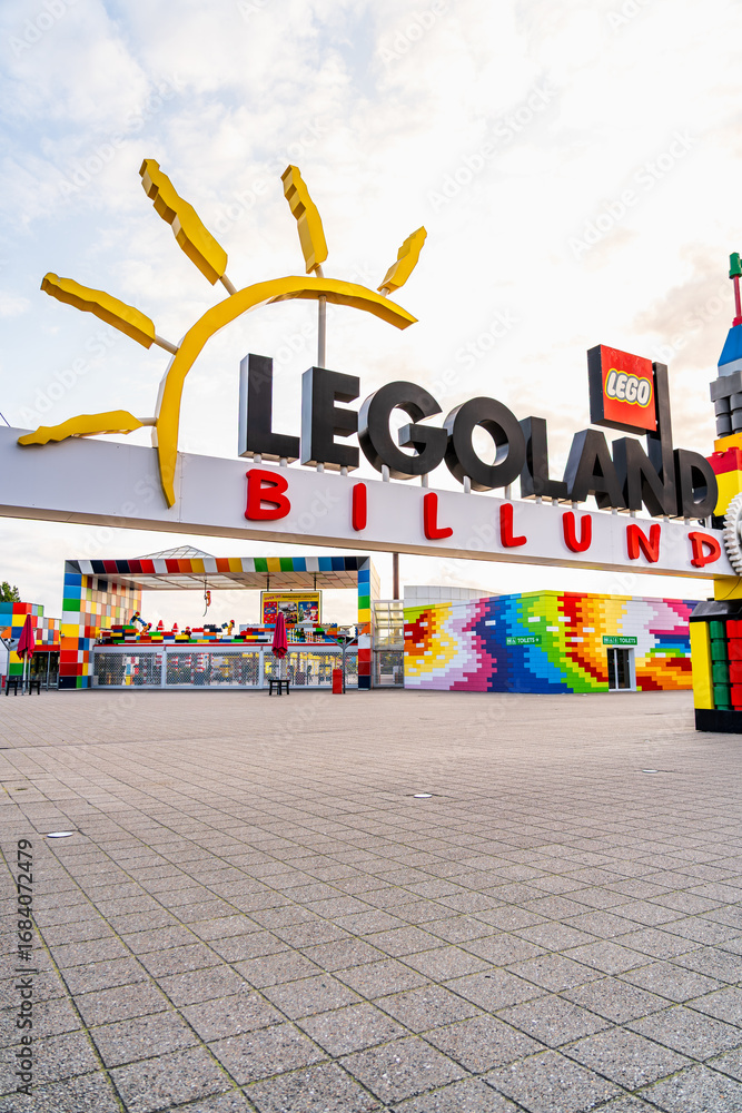 Naklejka premium A vibrant Gateway and entrance adorned with colorful structures welcomes visitors to Legoland Billund. The empty square offers a serene view during a warm summer evening after closing time