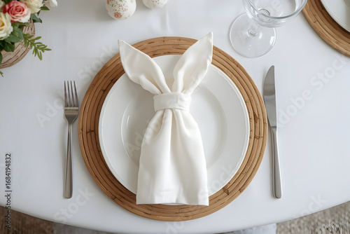 Elegant Easter table setting featuring a napkin folded into bunny ears on a plate and cutlery