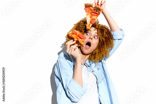 Excited young woman with curly hair holding slices of pizza, expressing joy and surprise against a white background, perfect for food enthusiasts and healthy eating concepts