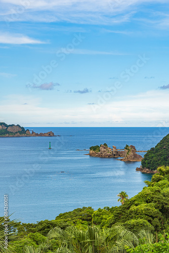 緑に囲まれた海岸線と沖に浮かぶ岩礁の自然風景