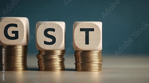 GST Text Displayed On Wooden Blocks Stacked Above Golden Coins Against Blue Backdrop
