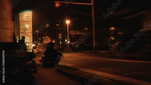 A city street at night, depicted with a blurred motion effect, highlighting the warm tones of the urban environment.