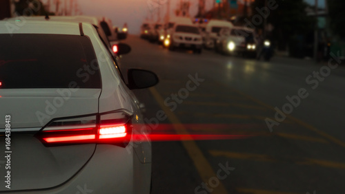 Abstract rear side car of white car with speed light from brake. Environment of asphalt road in the evening time with traffic jam of cars on the opposite side.