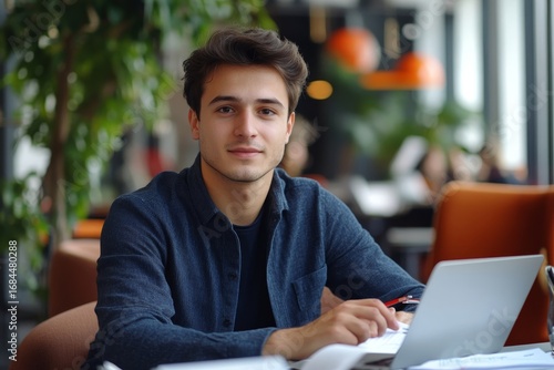Portrait of a young businessman, office worker who works in the office on a laptop and holds documents, bills, and agreements, looking at the camera with a confident smile, Generative AI
