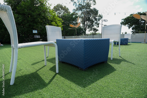 Angle view to woven plastic table and chairs outdoor hangout on the artificial grass.