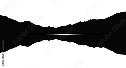 silhouette of mountains mirrored in still lake water at dawn or dusk