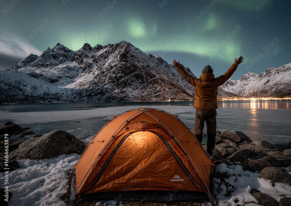 Fototapeta premium A man stands before a tent under the aurora borealis at night