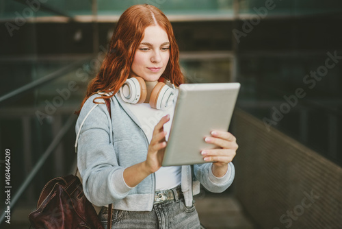 A young woman engages with her tablet in a lively city, showcasing a trendy, techsavvy life