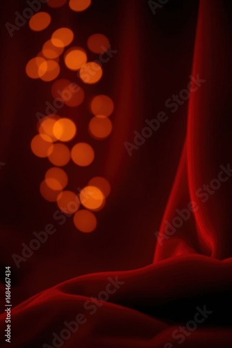 Soft red fabric drapes with glowing orange bokeh lights creating a dreamy atmosphere in a cozy setting