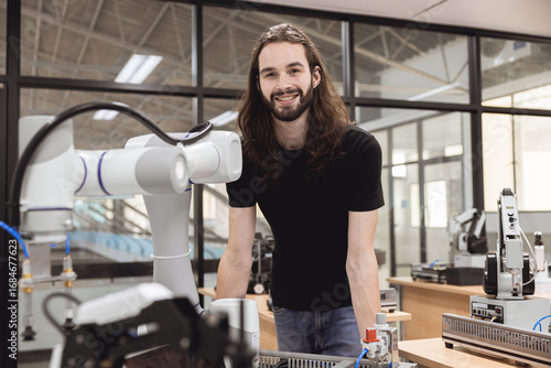 Bild auf Leinwand Portrait happy smile engineer male learning education in Industrial Robotics program with robot arm simulation model in university engineering lab classroom