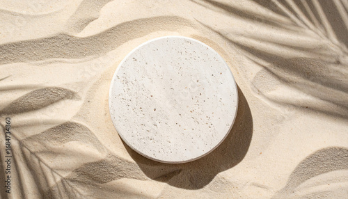 Round stone pedestal placed on soft sandy beach, flat lay. Pedestal for product presentation