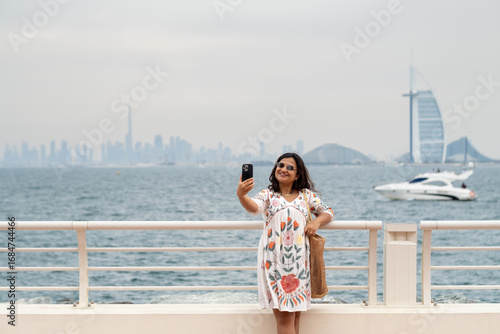 Photography Indian woman taking a selfie with Dubai skyline background, Stock photo of femal
