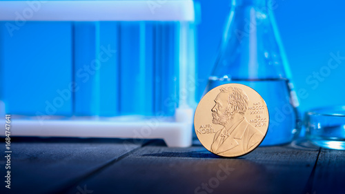 Nobel award against backdrop of chemical test tubes on blue background. Concept of scientific outstanding studies in field of chemistry and physics and key discoveries in motion in these areas.