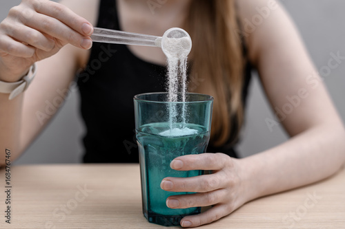 A woman dissolves fish collagen powder in a glass for healthy skin and joints.