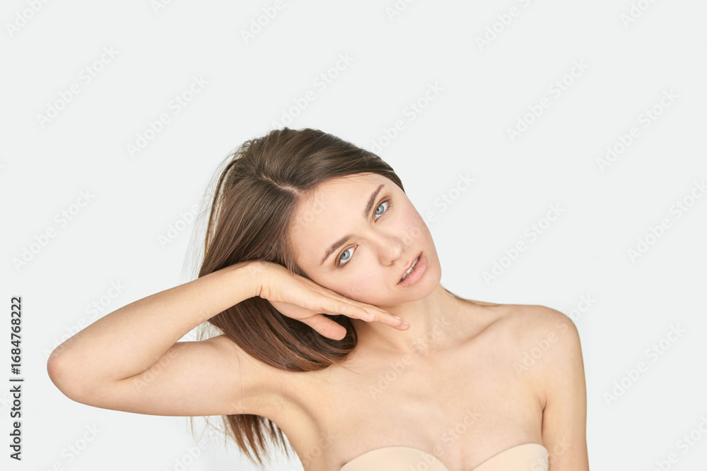Obraz premium Caucasian female young adult posing with head tilt and neutral expression against white background.