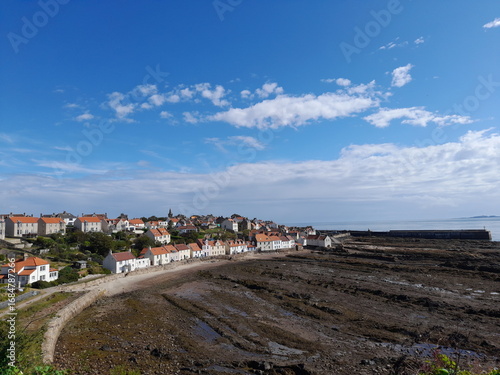 An above view of Pittenweem's coastline with the North Sea. The low tide reveals the rocky beach and forms rock pools filled with water reflecting the blue, clear sky. Taken in the East Neuk of Fife.